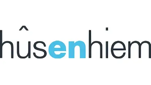 Logo van husenhiem met gestileerde zwarte tekst met een blauwe stip boven de 'i' en een kleine chevron boven de 'h'.